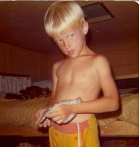 shirtless boy holding a snake