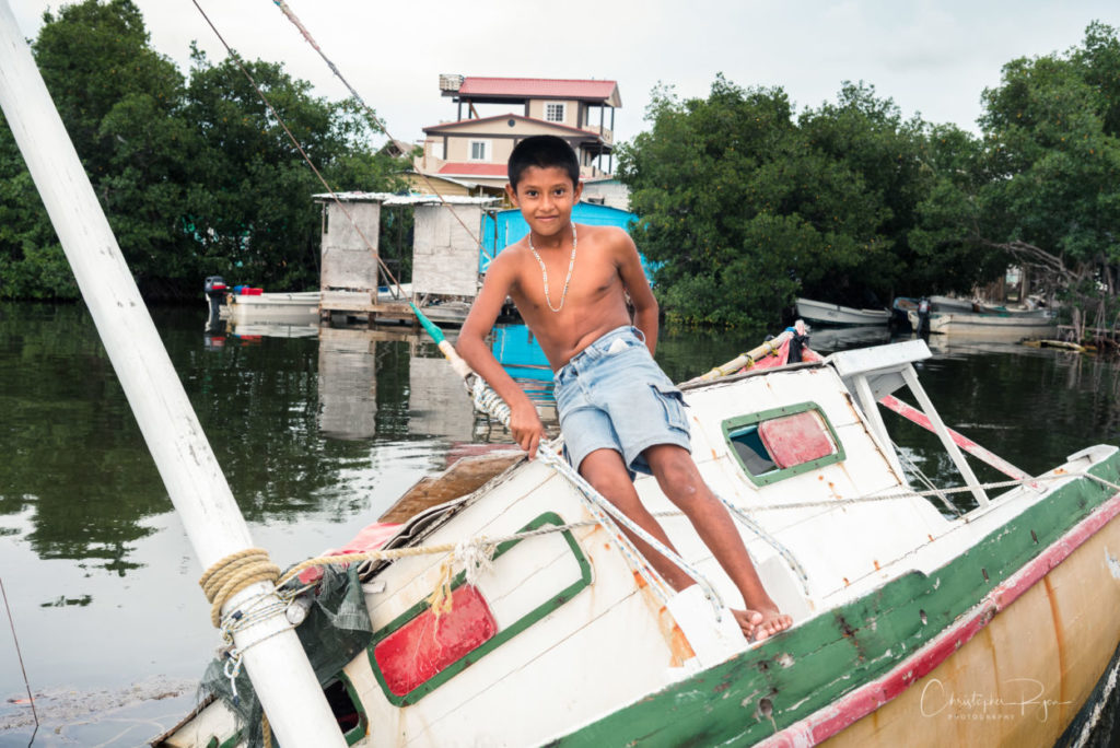 shirtless boy in jean shorts playing on an old boat