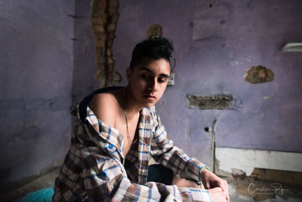 teen boy sitting in old room with his shoulder and upper chest exposed