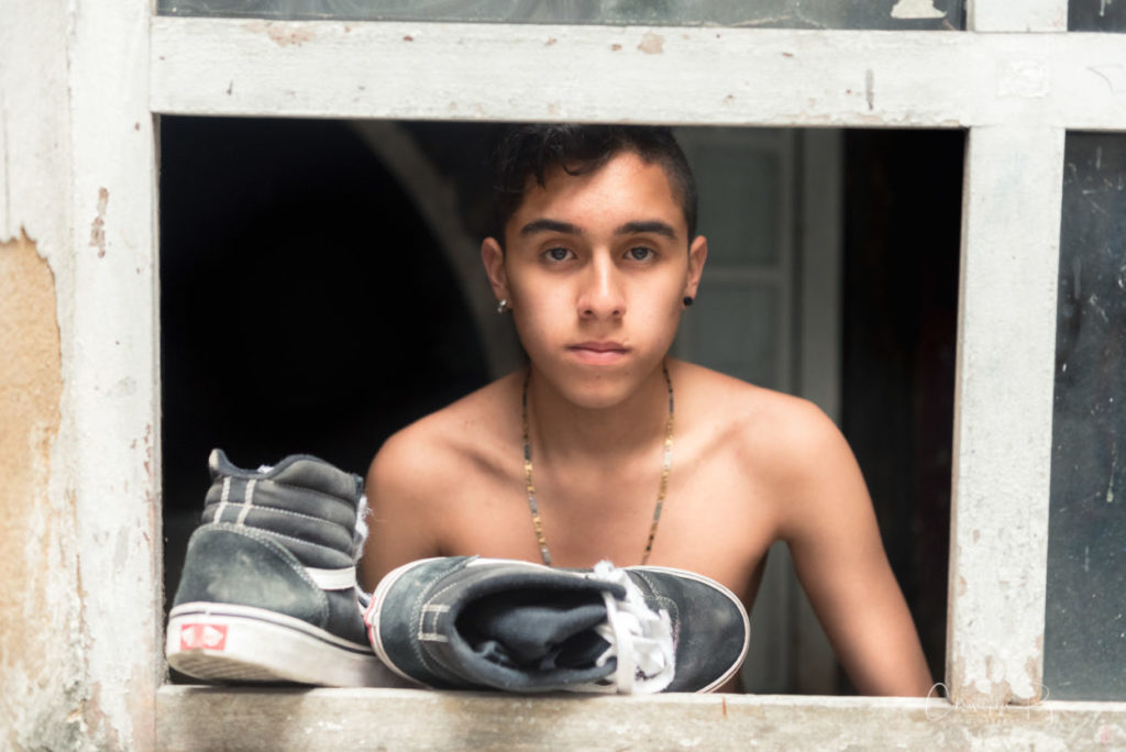 topless latino boy wearing a necklace shown with old sneakers in bogota colombia
