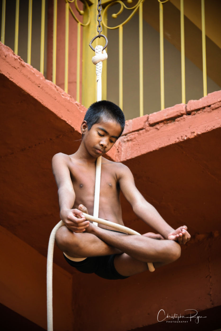 young shirtless 13 year old athletic boy in namaste pose on mallakhamb rope