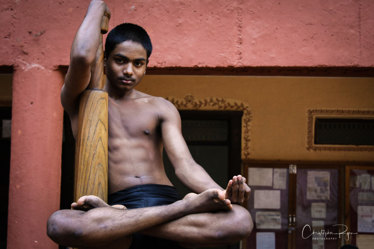 shirtless teen indian boy posing on mallakhamb pole