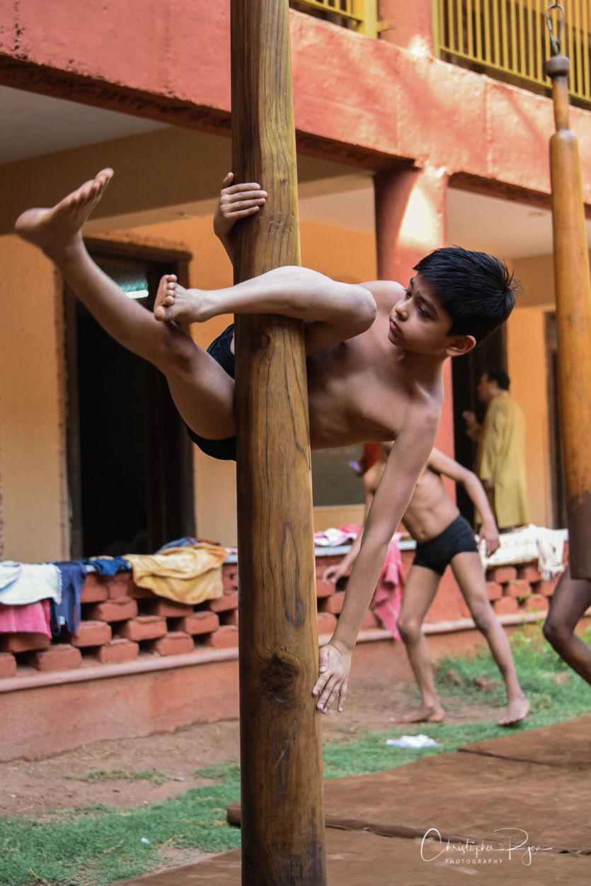 very young shirtless and barefoot boy performing on mallakhamb pole in india