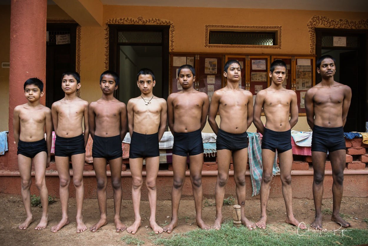 shirtless mallakhamb performers lined up at practice session