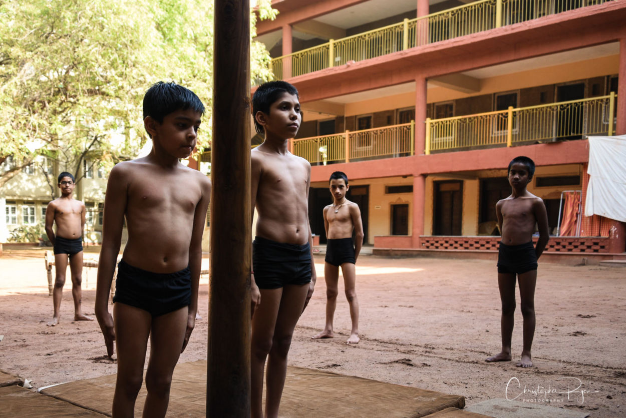 Shirtless athletic indian boys standing next to mallakhamb pole in ahmedabad india