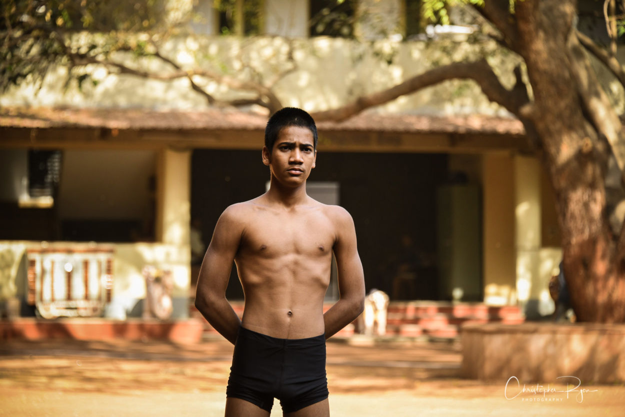 15 year old boy with defined body watching mallakhamb performers