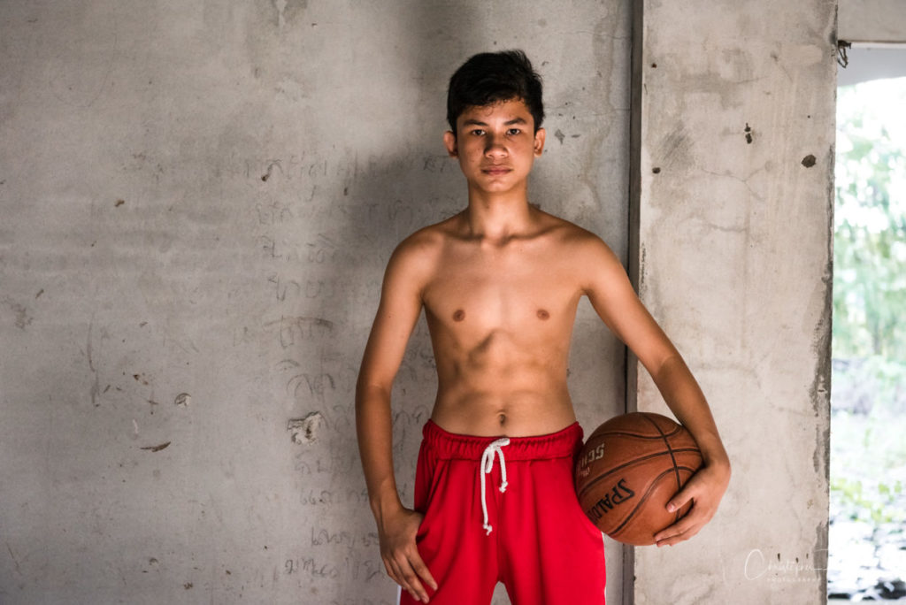 thin shirtless boy with nice abs holding a basketball.