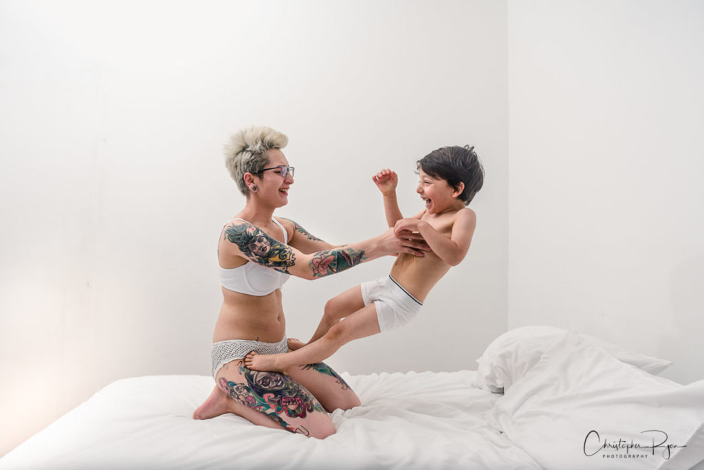mom throwing her young boy on a bed 