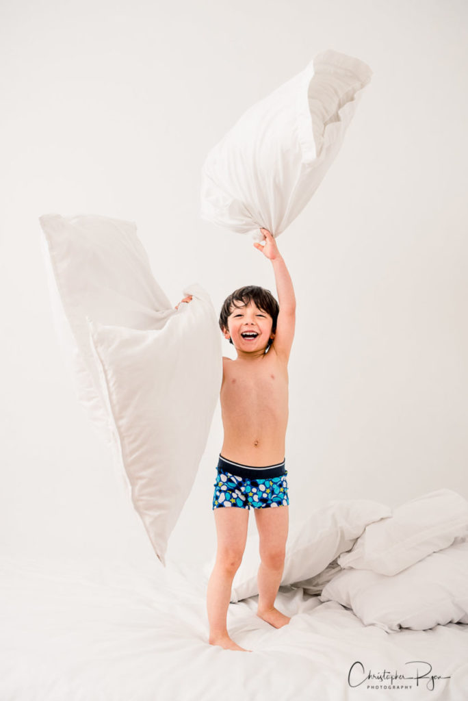 five year old boy in blue underwear playing with pillows
