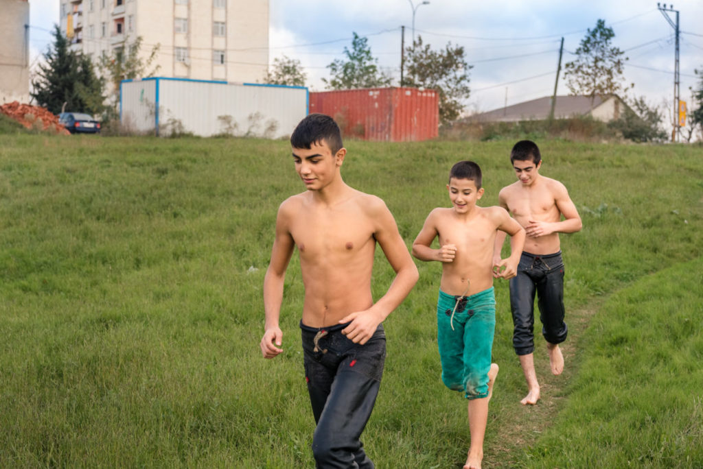 shirtless boys running through a field