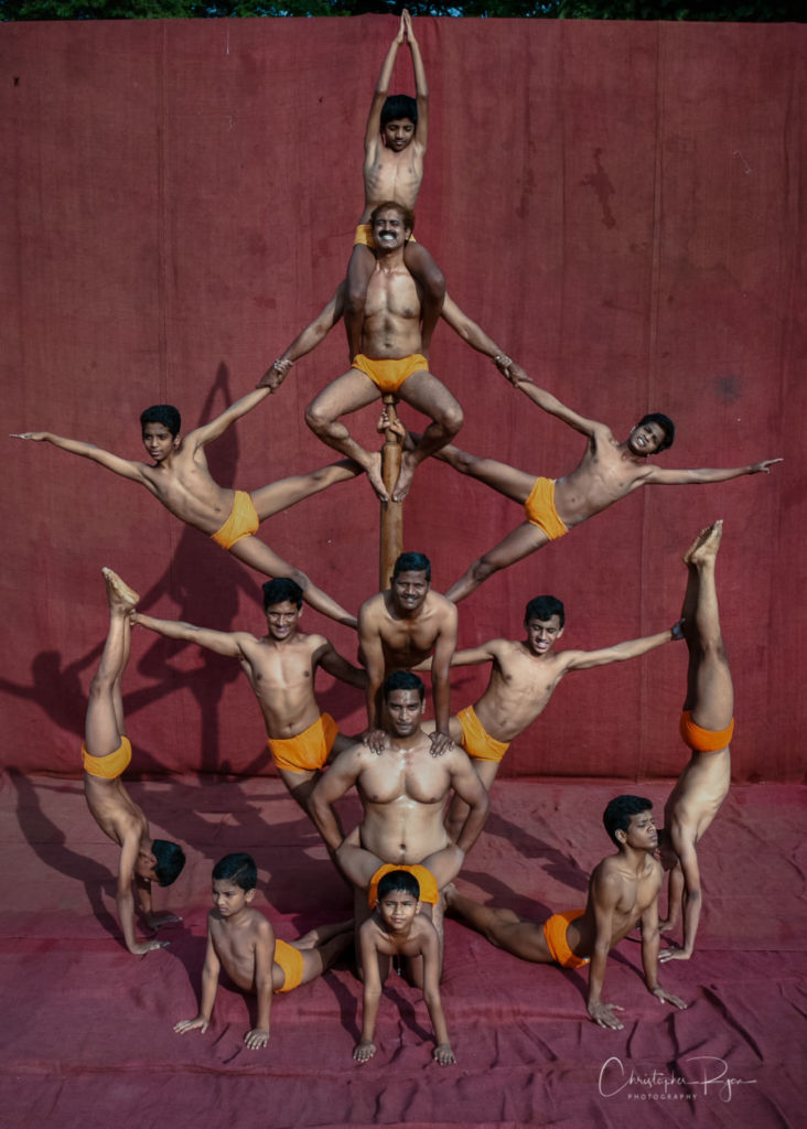 shirtless male mallakhamb performers demonstrating an intricate pose in Mumbai, India