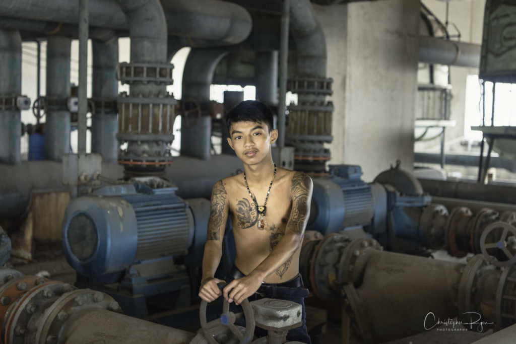 shirtless teenage boy with tattoos in abandoned building in bangkok thailand