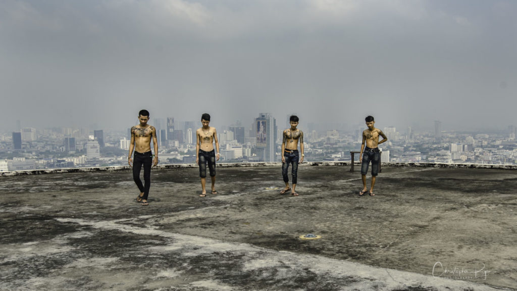 group of shirtless boys on the roof of a skyscraper